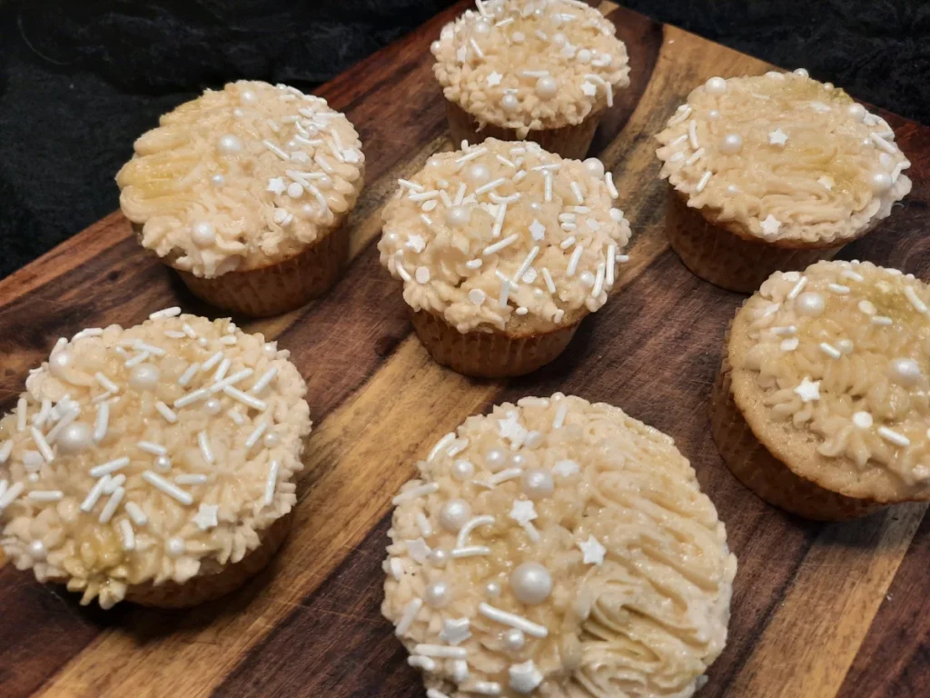Collection of 7 chai spice cupcakes, each frosted and decorated with sprinkles.